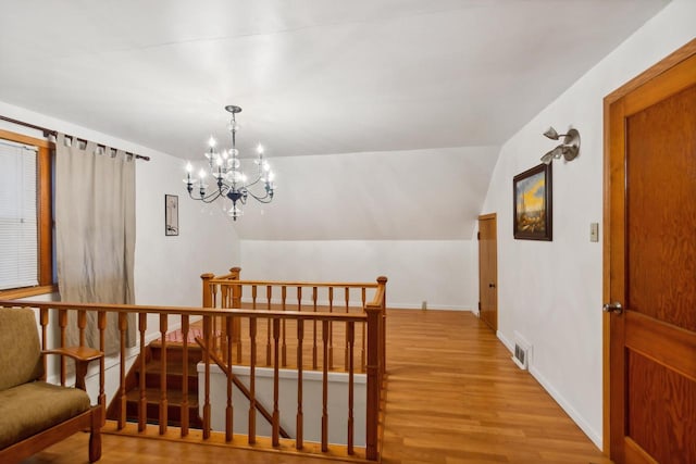 interior space featuring a notable chandelier, light hardwood / wood-style floors, and vaulted ceiling