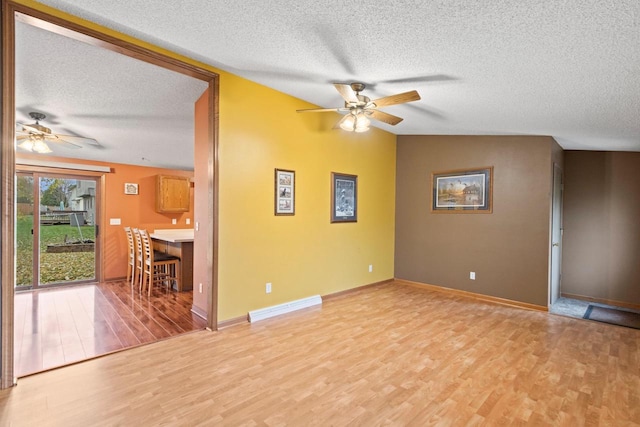 interior space with vaulted ceiling, ceiling fan, a textured ceiling, and light wood-type flooring