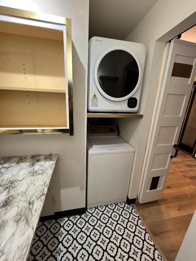 washroom with wood-type flooring and stacked washing maching and dryer