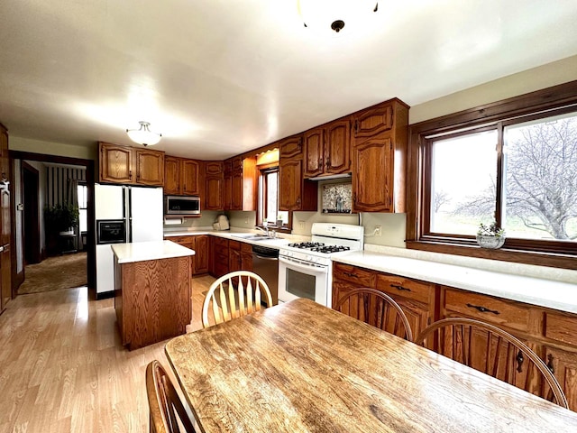 kitchen with sink, a center island, light wood-type flooring, and appliances with stainless steel finishes