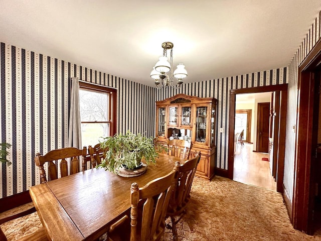 dining space with light hardwood / wood-style floors and a notable chandelier