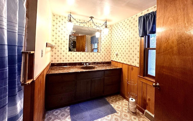 bathroom with vanity, a healthy amount of sunlight, and wood walls