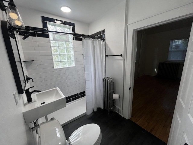 bathroom featuring a shower with shower curtain, sink, hardwood / wood-style flooring, radiator heating unit, and toilet