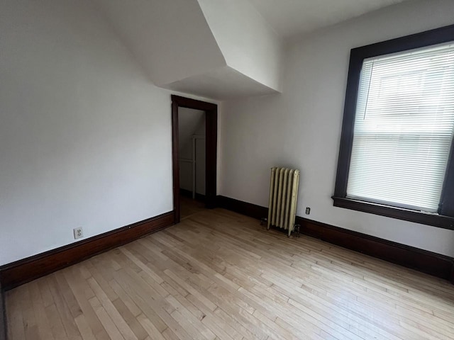 spare room featuring light wood-type flooring and radiator