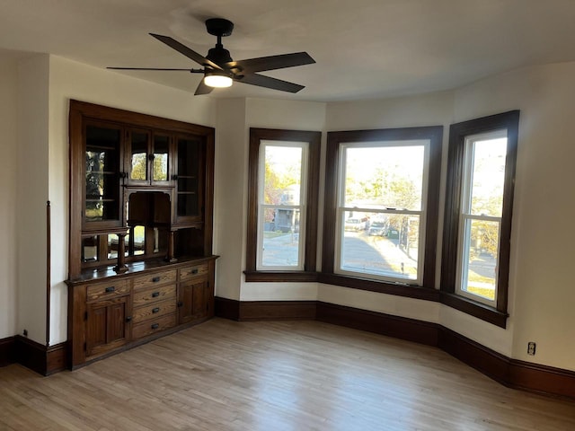 unfurnished dining area featuring a wealth of natural light, ceiling fan, and light wood-type flooring