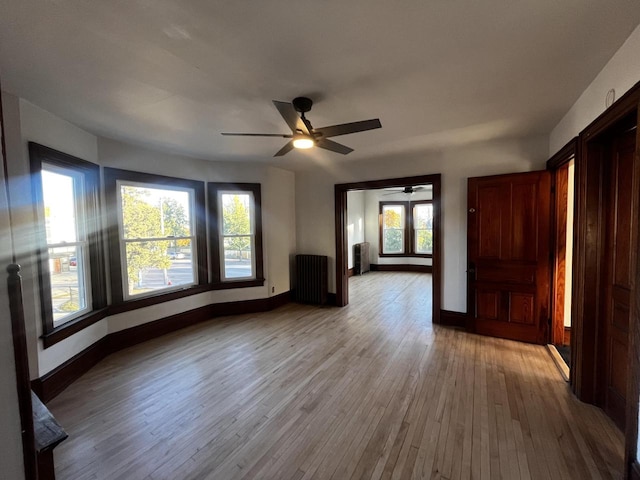 unfurnished room featuring ceiling fan, light hardwood / wood-style floors, and radiator