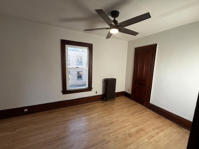 spare room with ceiling fan, radiator heating unit, and light hardwood / wood-style flooring