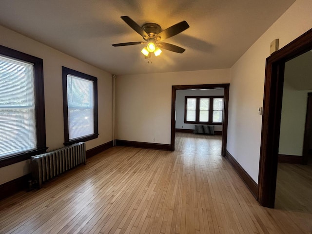 unfurnished room featuring ceiling fan, radiator heating unit, and light hardwood / wood-style flooring