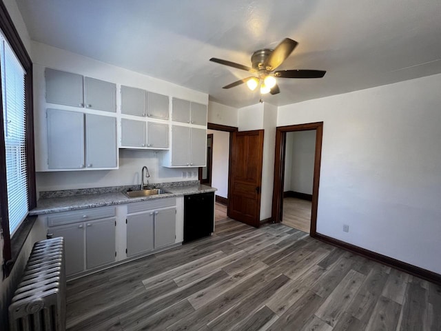 kitchen with dark wood-type flooring, radiator, sink, ceiling fan, and black dishwasher