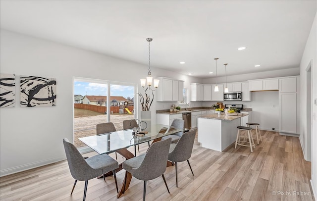 dining area with light hardwood / wood-style floors, an inviting chandelier, and sink