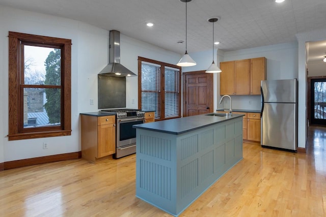 kitchen featuring sink, stainless steel appliances, wall chimney range hood, pendant lighting, and light wood-type flooring