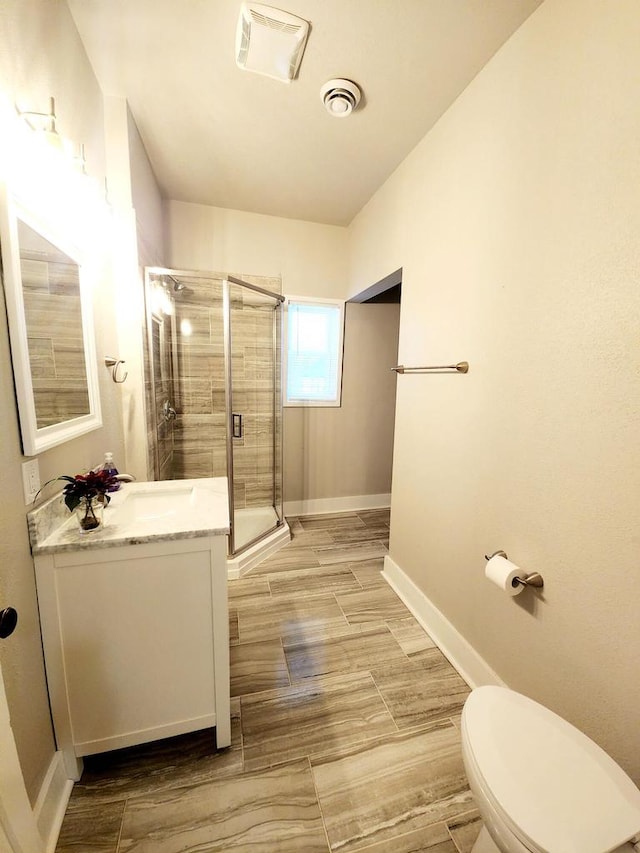 bathroom with hardwood / wood-style floors, vanity, toilet, and walk in shower