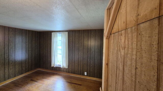 33135 Fulton St, Lone Rock, WI 53556 - empty room with wood finished floors, wooden walls, baseboards, and a textured ceiling