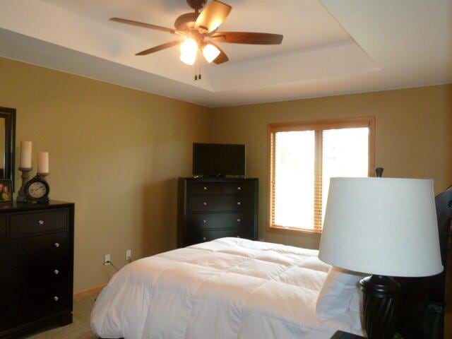 bedroom with carpet flooring, ceiling fan, and a tray ceiling