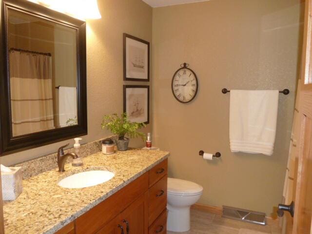 bathroom with curtained shower, vanity, and toilet