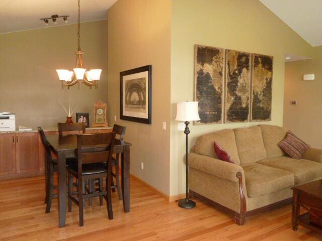 dining room featuring light hardwood / wood-style floors, high vaulted ceiling, and an inviting chandelier