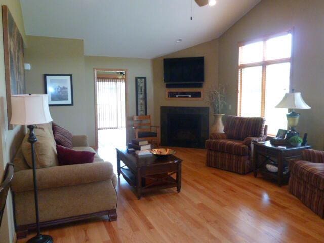 living room with ceiling fan, lofted ceiling, and light wood-type flooring