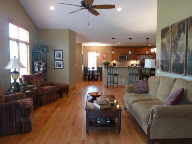 living room featuring a wealth of natural light, light hardwood / wood-style flooring, ceiling fan, and vaulted ceiling