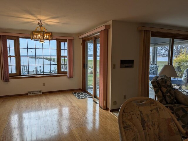 interior space featuring a water view, a chandelier, and light wood-type flooring