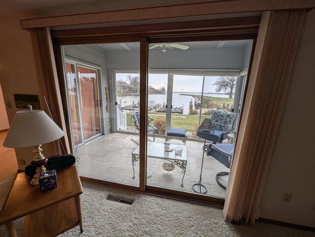 doorway to outside featuring carpet floors, ceiling fan, and a water view