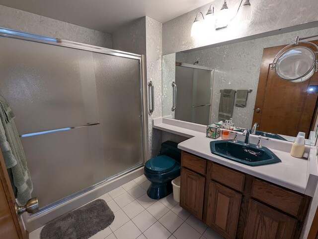 bathroom with tile patterned flooring, vanity, toilet, and an enclosed shower