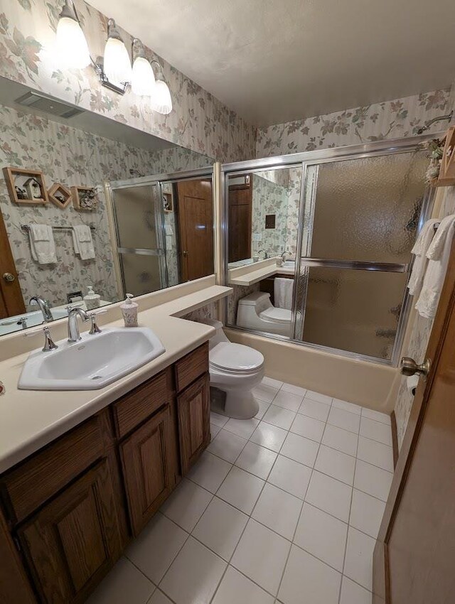 full bathroom with tile patterned floors, vanity, toilet, and bath / shower combo with glass door