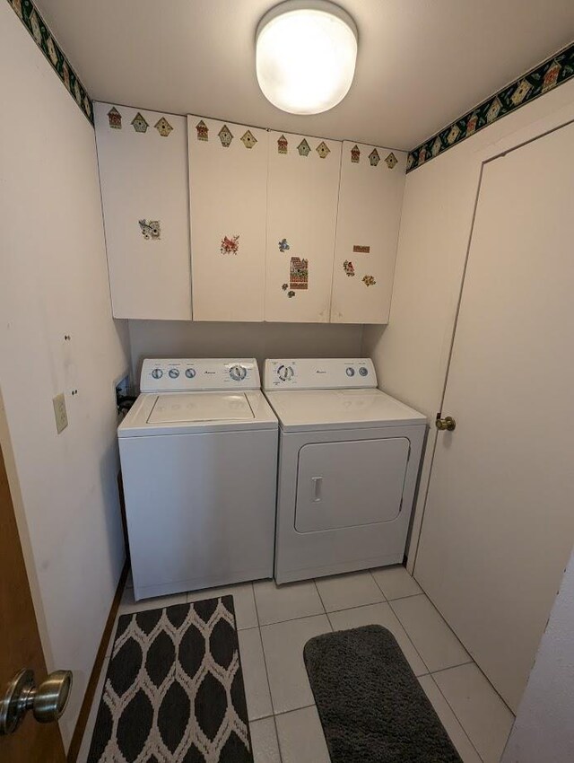 washroom with washing machine and clothes dryer, light tile patterned floors, and cabinets