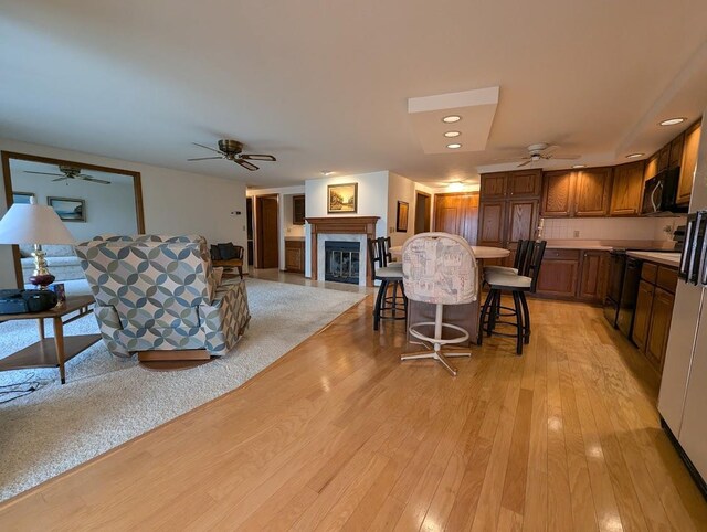 kitchen featuring black appliances, a kitchen bar, a fireplace, and light hardwood / wood-style flooring