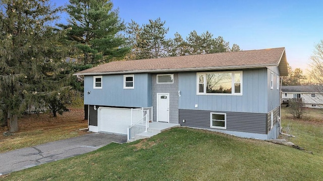 raised ranch featuring a yard and a garage