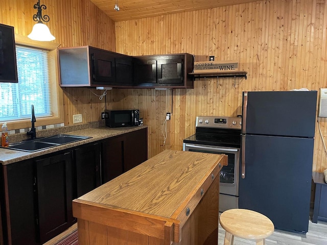 kitchen with wooden walls, fridge, stainless steel range with electric cooktop, and sink