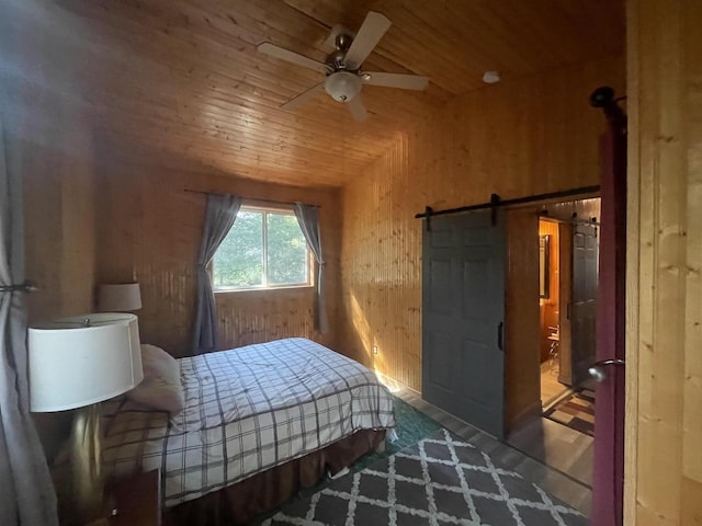 bedroom featuring wood walls, ceiling fan, a barn door, and wooden ceiling