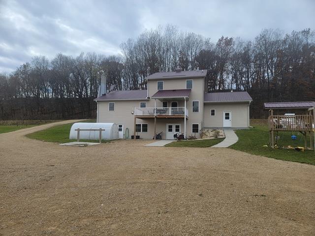 rear view of property featuring a pool side deck and a yard