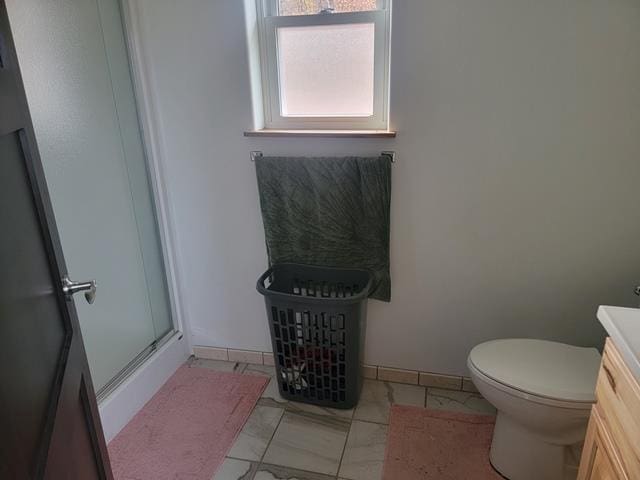 bathroom with vanity, toilet, and a shower with door