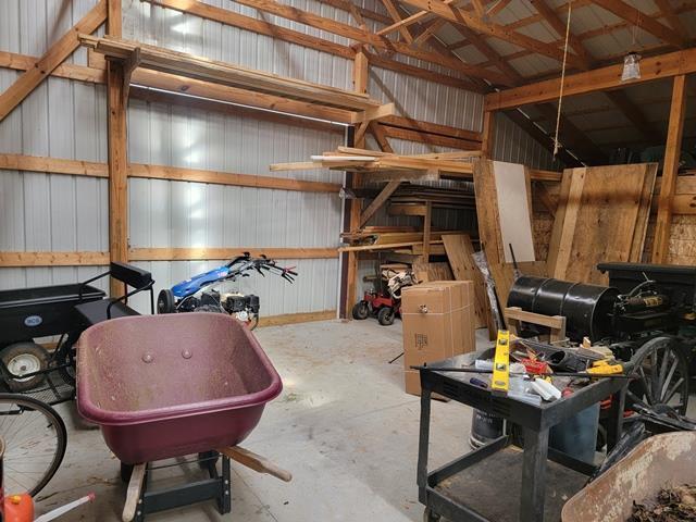 misc room with wood walls, concrete flooring, and vaulted ceiling