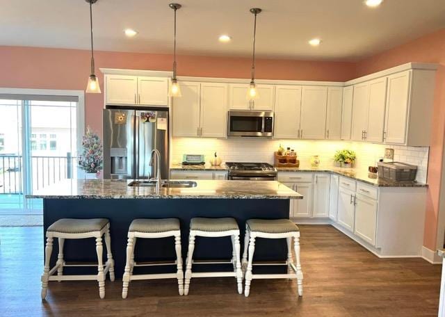 kitchen with white cabinets, pendant lighting, appliances with stainless steel finishes, and dark stone counters