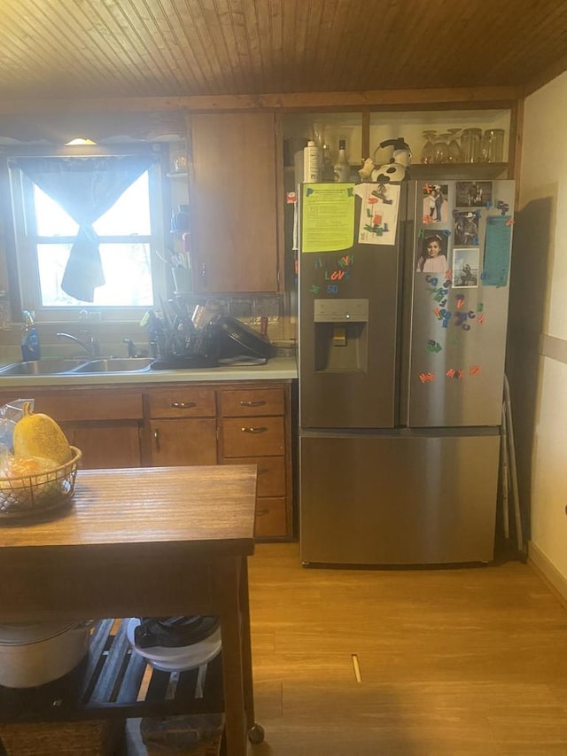 kitchen featuring stainless steel fridge, sink, light hardwood / wood-style floors, and wooden ceiling