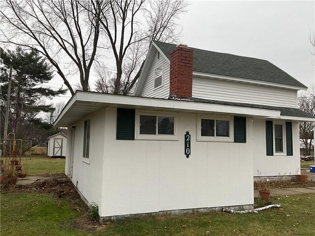 view of home's exterior with a storage shed and a yard