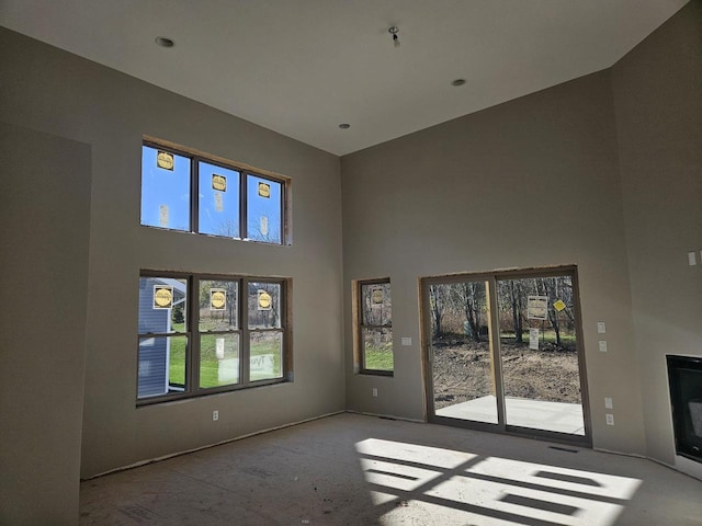 unfurnished living room with a high ceiling and a healthy amount of sunlight