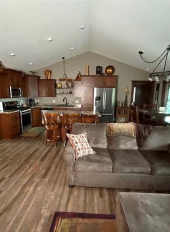 living room featuring hardwood / wood-style floors, sink, lofted ceiling, and a notable chandelier