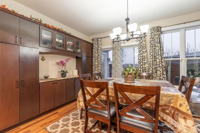 dining space with light hardwood / wood-style floors and a notable chandelier