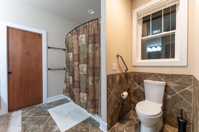 bathroom with curtained shower, toilet, and tile walls