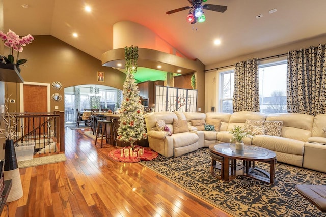 living room with hardwood / wood-style flooring, ceiling fan, and high vaulted ceiling