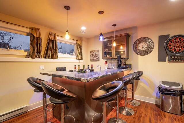 bar with dark wood-type flooring, decorative light fixtures, and a baseboard heating unit