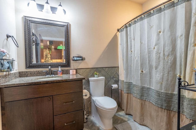 bathroom featuring vanity, curtained shower, toilet, and tile walls