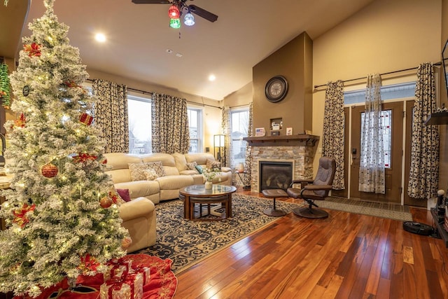 living room featuring ceiling fan, a fireplace, high vaulted ceiling, and wood-type flooring