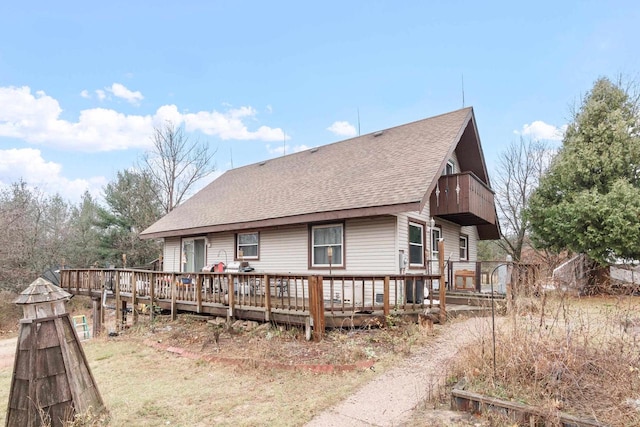 back of house featuring a balcony and a wooden deck