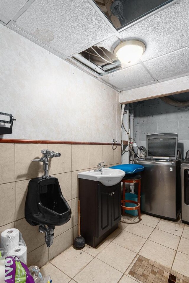 clothes washing area with light tile patterned floors, washer and clothes dryer, and sink