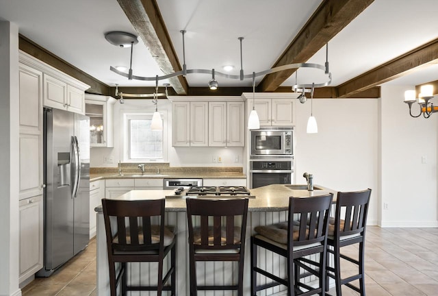 kitchen with stainless steel appliances, white cabinetry, and a center island with sink