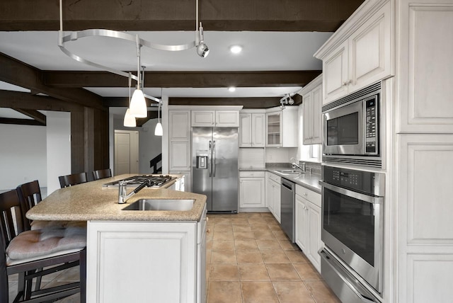 kitchen with appliances with stainless steel finishes, a breakfast bar, a kitchen island with sink, white cabinets, and hanging light fixtures