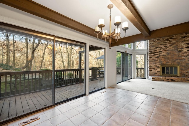 interior space with a chandelier, beam ceiling, plenty of natural light, and a fireplace